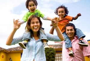 family portrait of happy family with kids resting on parents' shoulders