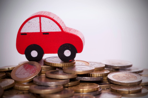 Red car driving over pile of coins